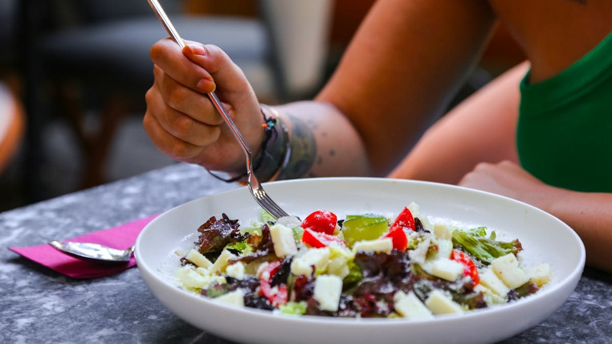 A close-up view of a colorful salad being eaten with a fork indoors. Perfect for food photography.